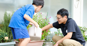 スタッフと子供が植物に水をあげるシーン