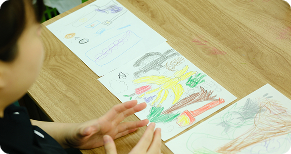 子供が描いた絵を見ているスタッフ