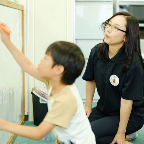 絵を描く子供を見守る柿沼 みどりさん